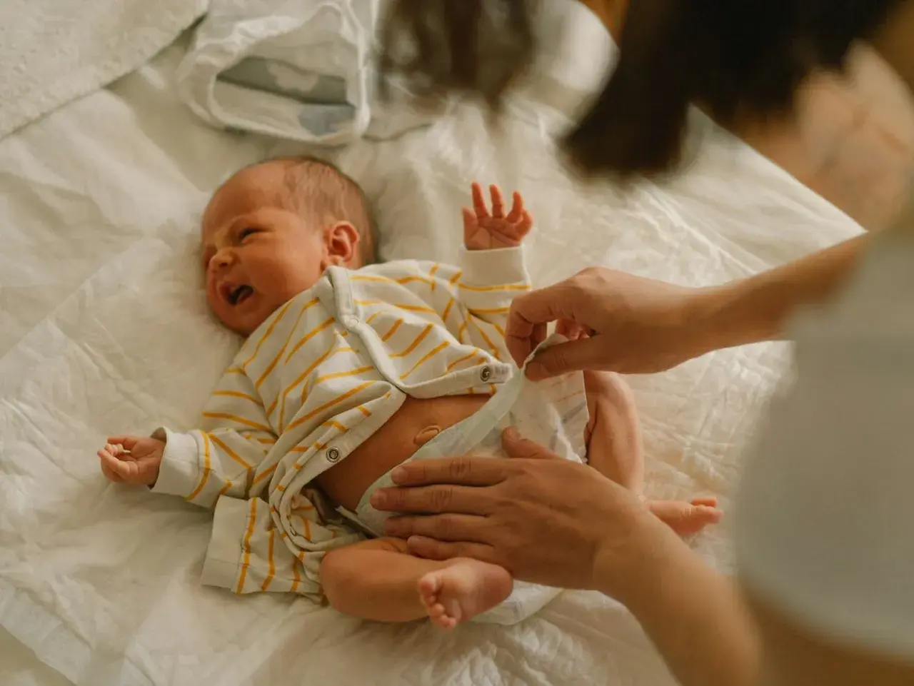Mama zmienia pieluchę noworodkowi. Wybór odpowiednich pieluch dla noworodka to ważna decyzja.