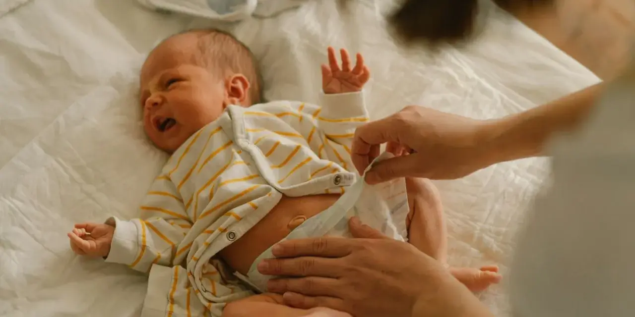 Mama zmienia pieluchę noworodkowi. Wybór odpowiednich pieluch dla noworodka to ważna decyzja.