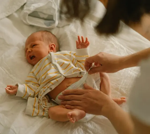 Mama zmienia pieluchę noworodkowi. Wybór odpowiednich pieluch dla noworodka to ważna decyzja.